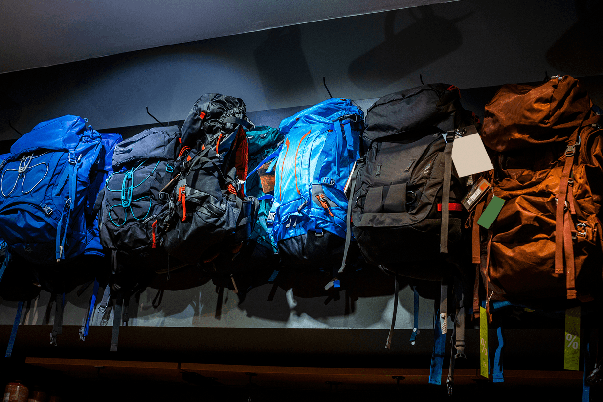 Backpacks displayed on a dark wall shelf.